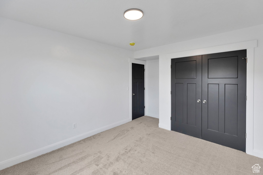 Unfurnished bedroom featuring light carpet and a closet