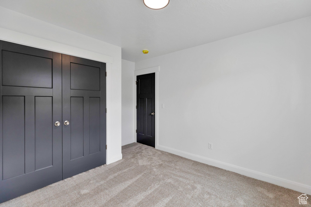 Unfurnished bedroom with a closet and light carpet