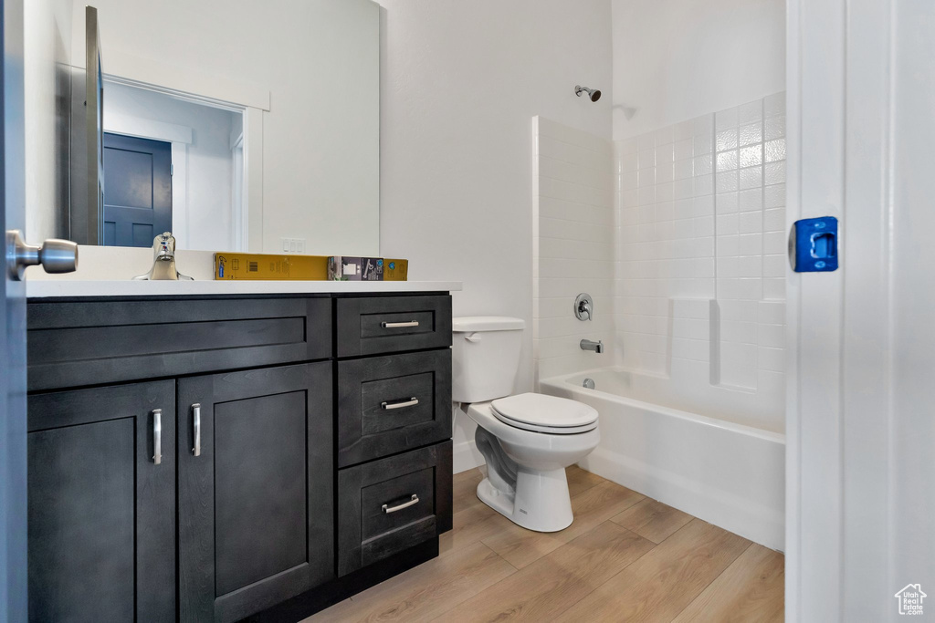 Full bathroom with vanity, hardwood / wood-style floors, toilet, and washtub / shower combination