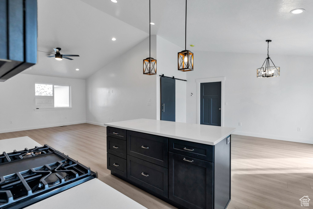 Kitchen featuring a barn door, light hardwood / wood-style floors, decorative light fixtures, and vaulted ceiling