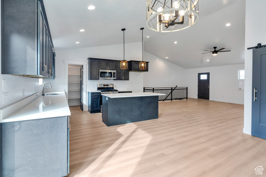 Kitchen featuring pendant lighting, lofted ceiling, a kitchen island, stainless steel appliances, and a barn door