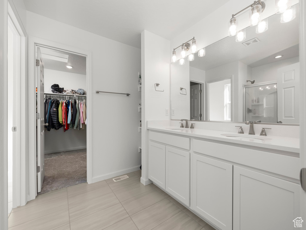 Bathroom with vanity, a shower with shower door, and tile patterned floors