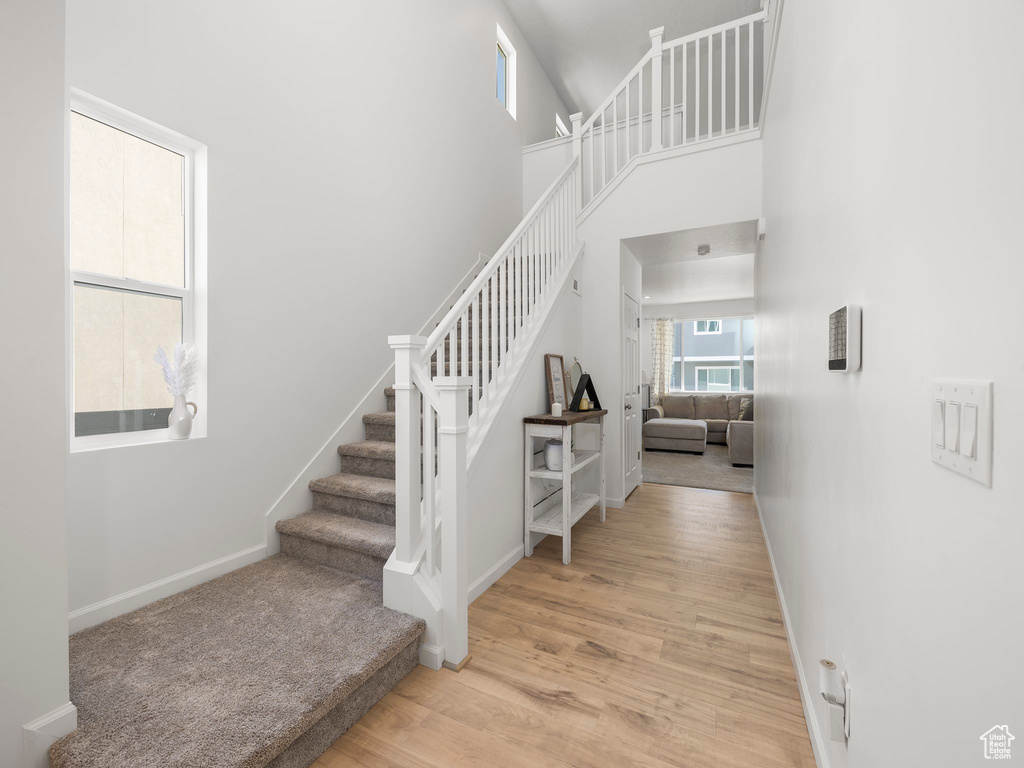 Stairway with a towering ceiling and hardwood / wood-style floors