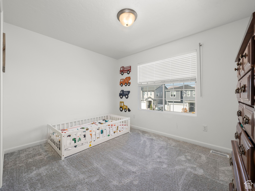 Unfurnished bedroom with a nursery area and carpet flooring