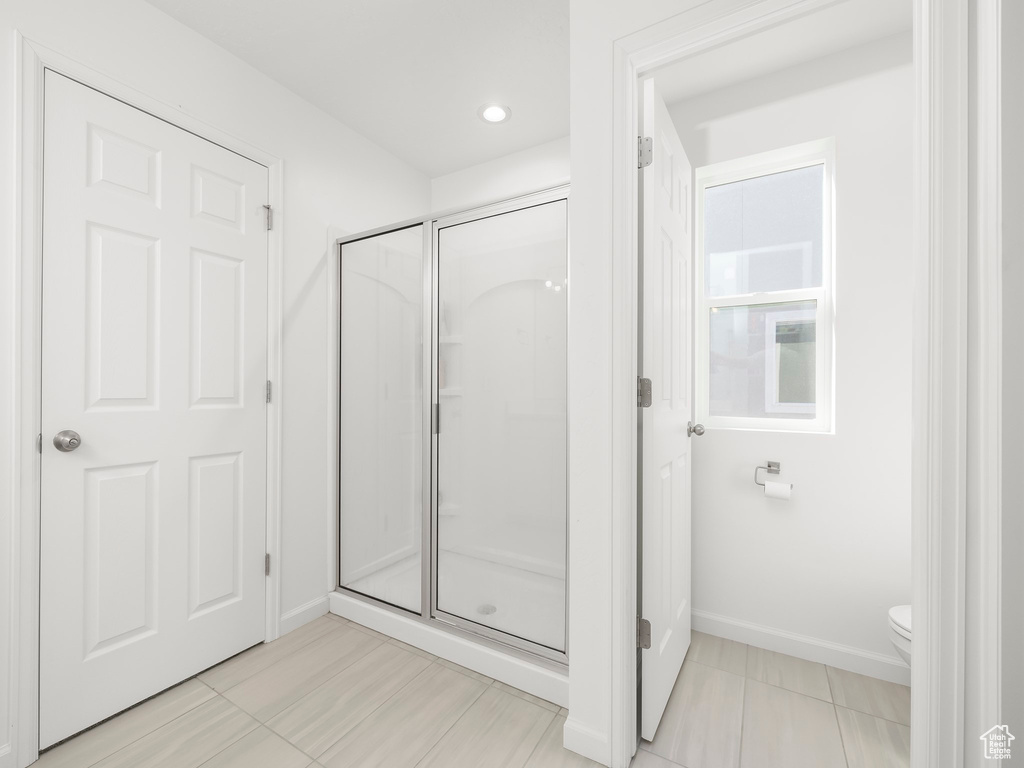 Bathroom featuring walk in shower, tile patterned flooring, and toilet