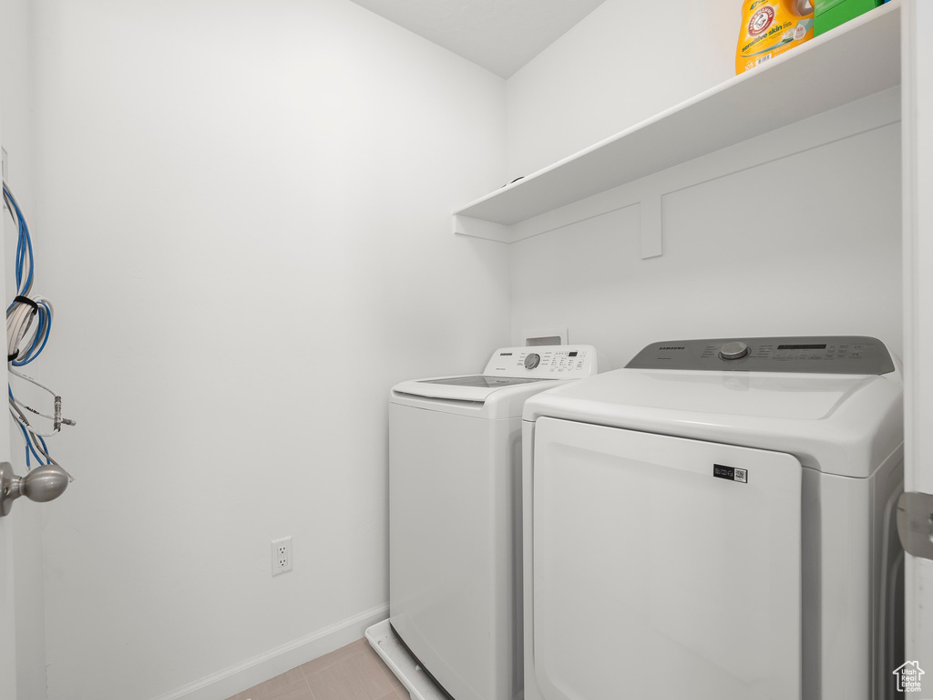 Laundry area with light tile patterned flooring and separate washer and dryer