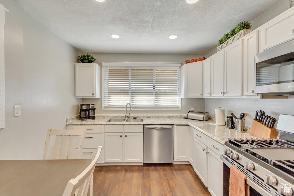 Kitchen featuring stainless steel appliances, light wood-type flooring, sink, and white cabinetry