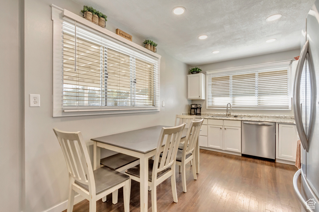 Kitchen with white cabinets, appliances with stainless steel finishes, dark hardwood / wood-style floors, and a wealth of natural light