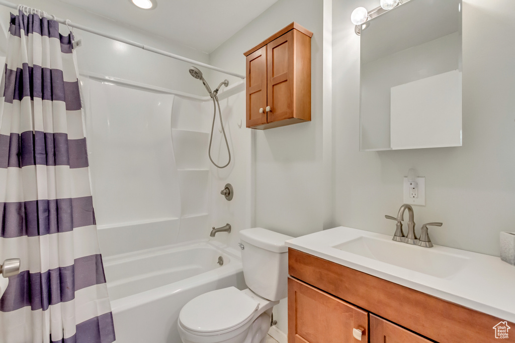 Full bathroom featuring vanity, toilet, and shower / bathtub combination with curtain