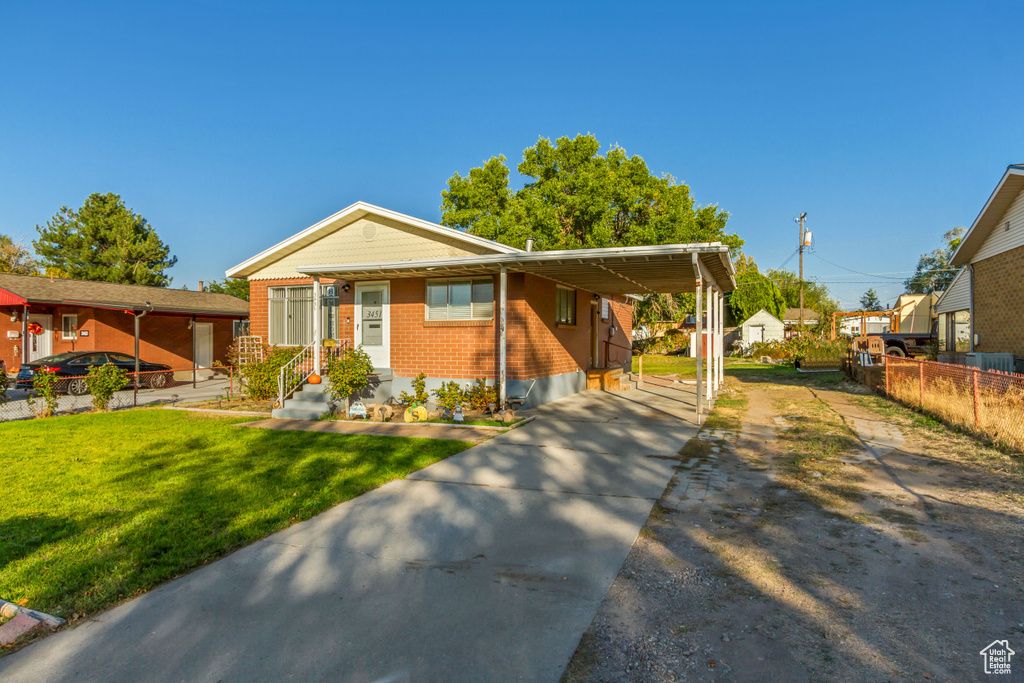 View of front facade featuring a carport and a front yard