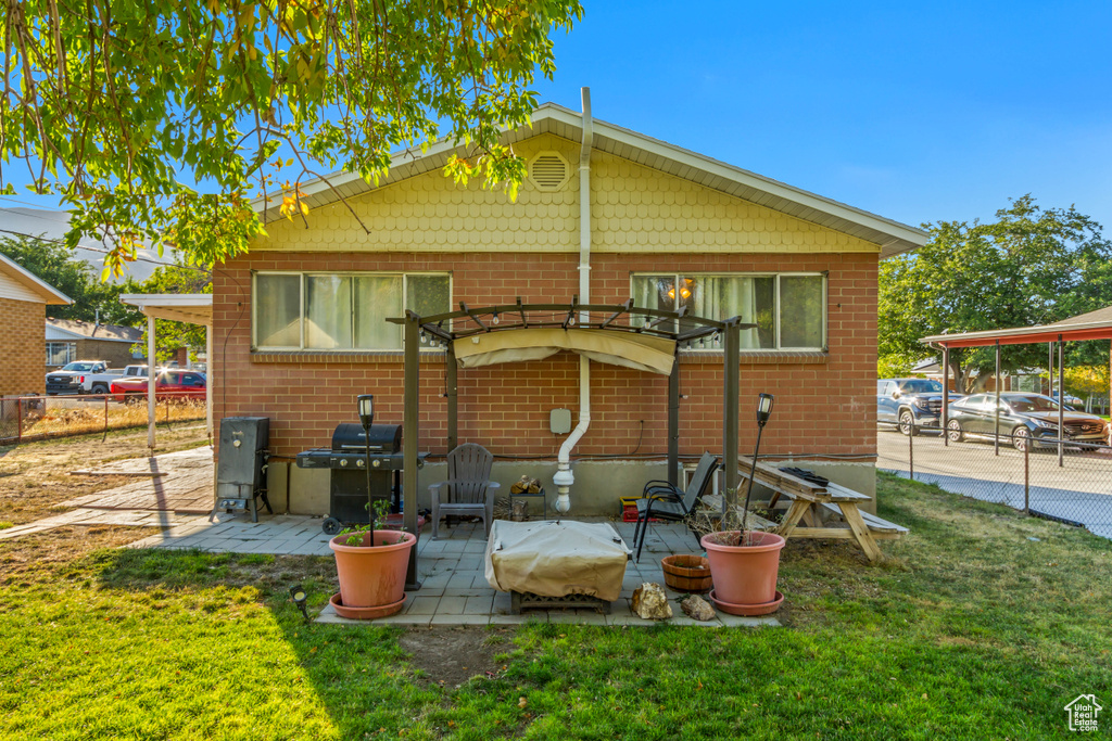 Back of house with a yard, a carport, and a patio area