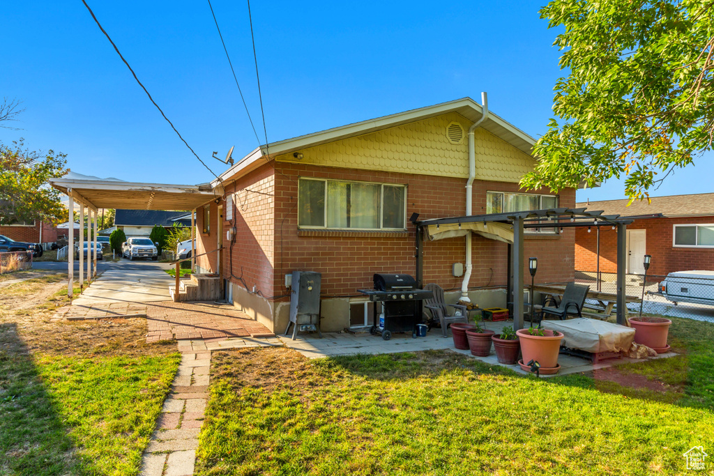 Rear view of house with a lawn, a patio, and a carport