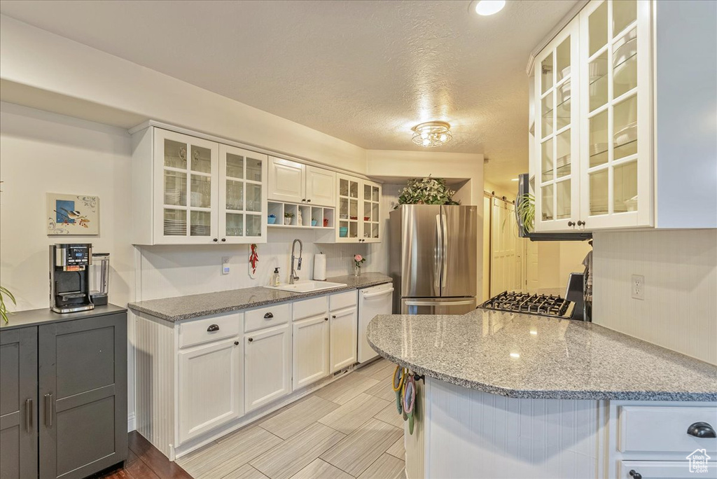 Kitchen with white cabinets, a textured ceiling, stainless steel appliances, and sink