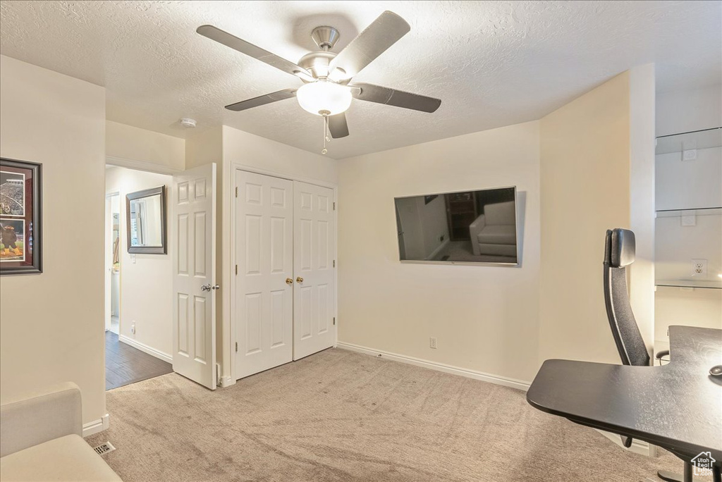 Interior space with ceiling fan and a textured ceiling