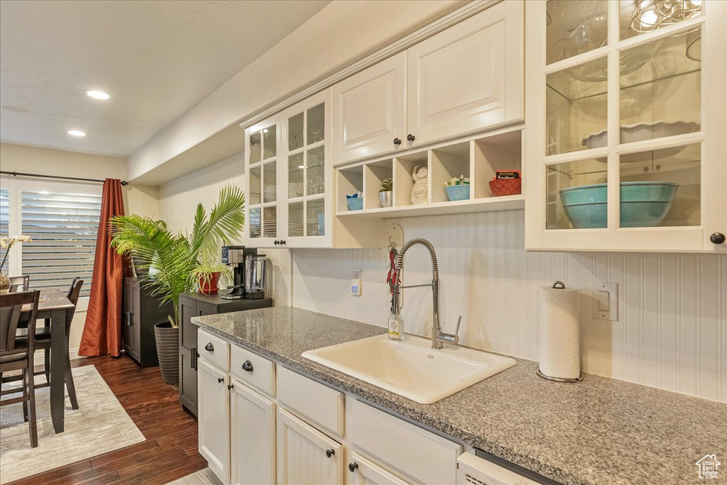 Kitchen with light stone counters, sink, dark hardwood / wood-style flooring, and white cabinetry