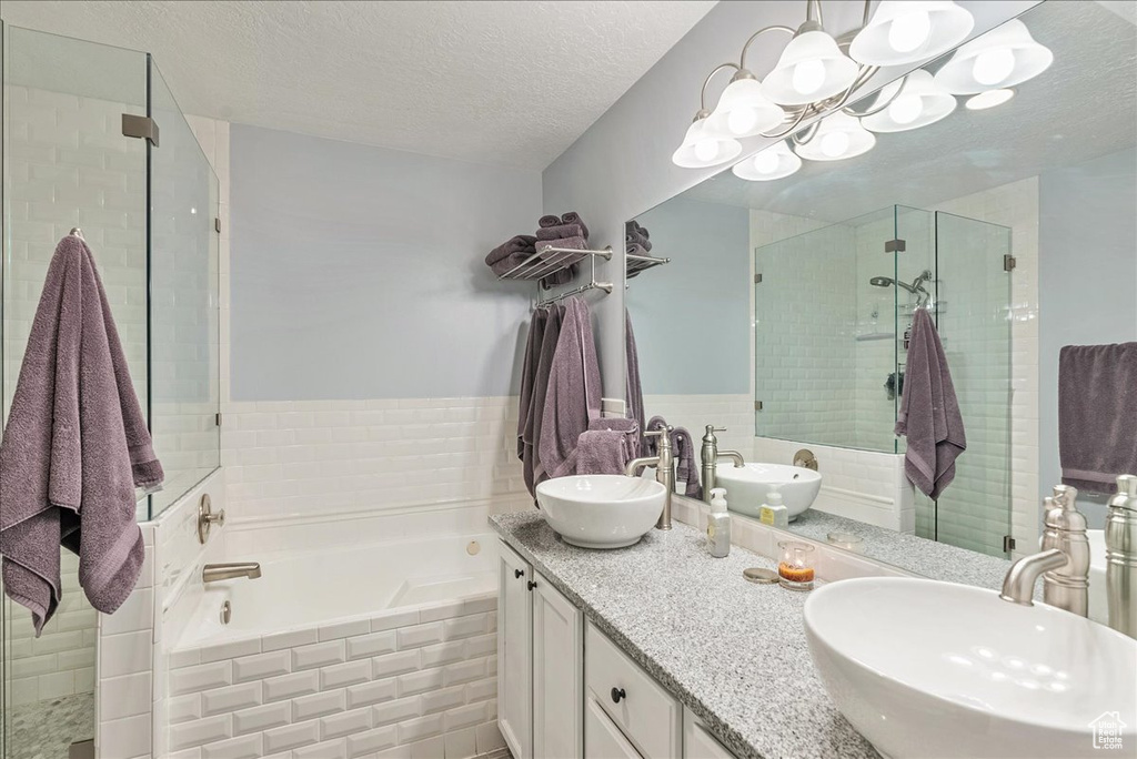 Bathroom with separate shower and tub, vanity, tile walls, and a textured ceiling