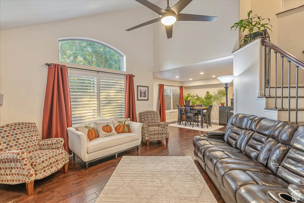 Living room featuring ceiling fan, a towering ceiling, and dark hardwood / wood-style floors