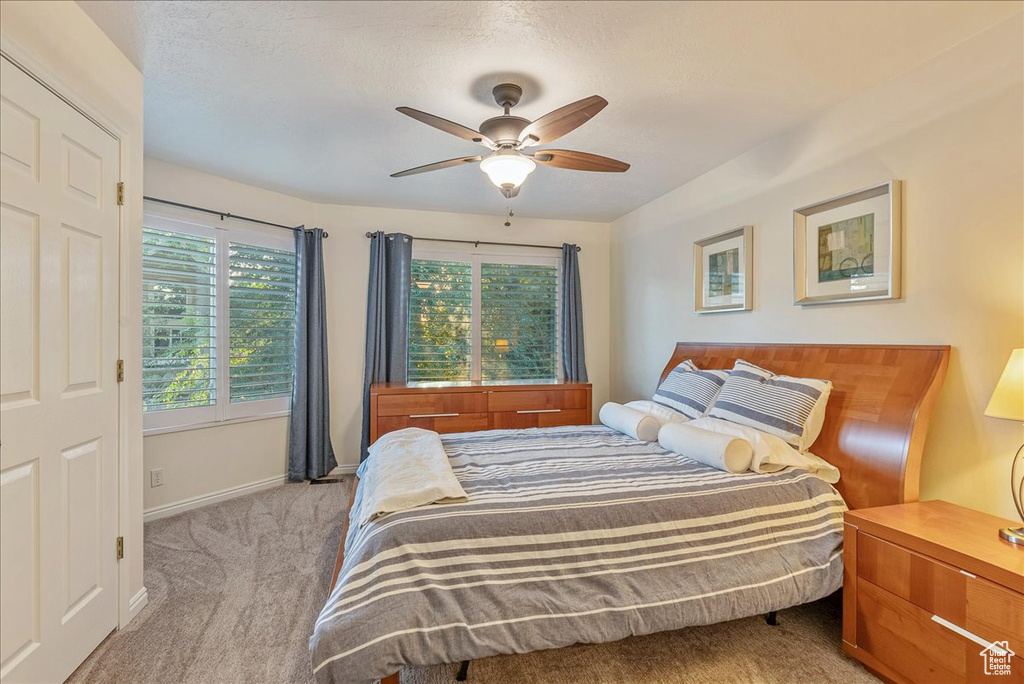 Bedroom featuring light carpet, ceiling fan, and a textured ceiling