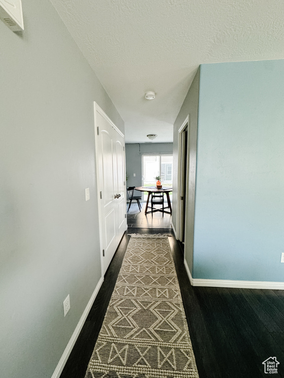 Corridor with a textured ceiling and dark hardwood / wood-style floors