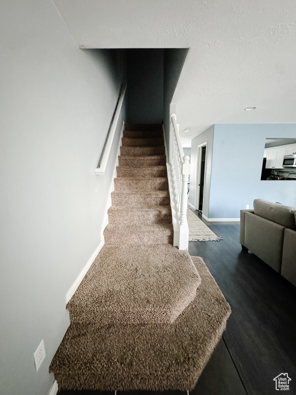 Staircase with hardwood / wood-style floors and a textured ceiling