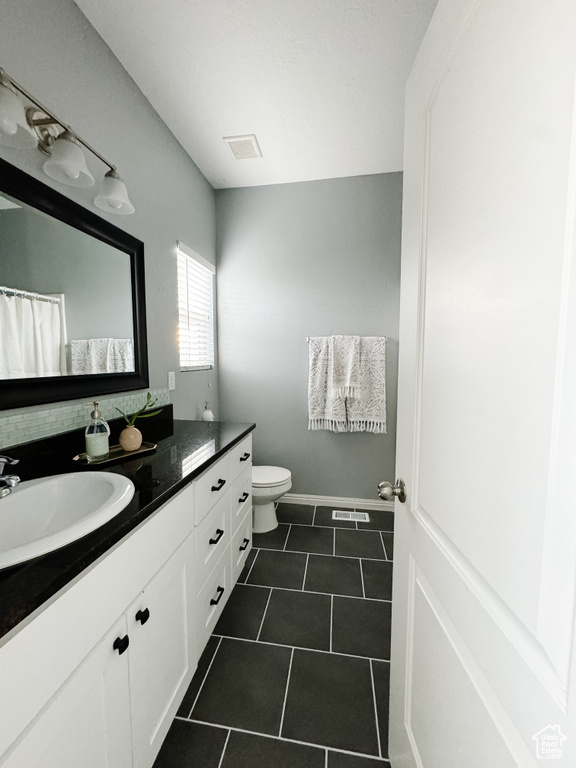 Bathroom with vanity, toilet, and tile patterned floors