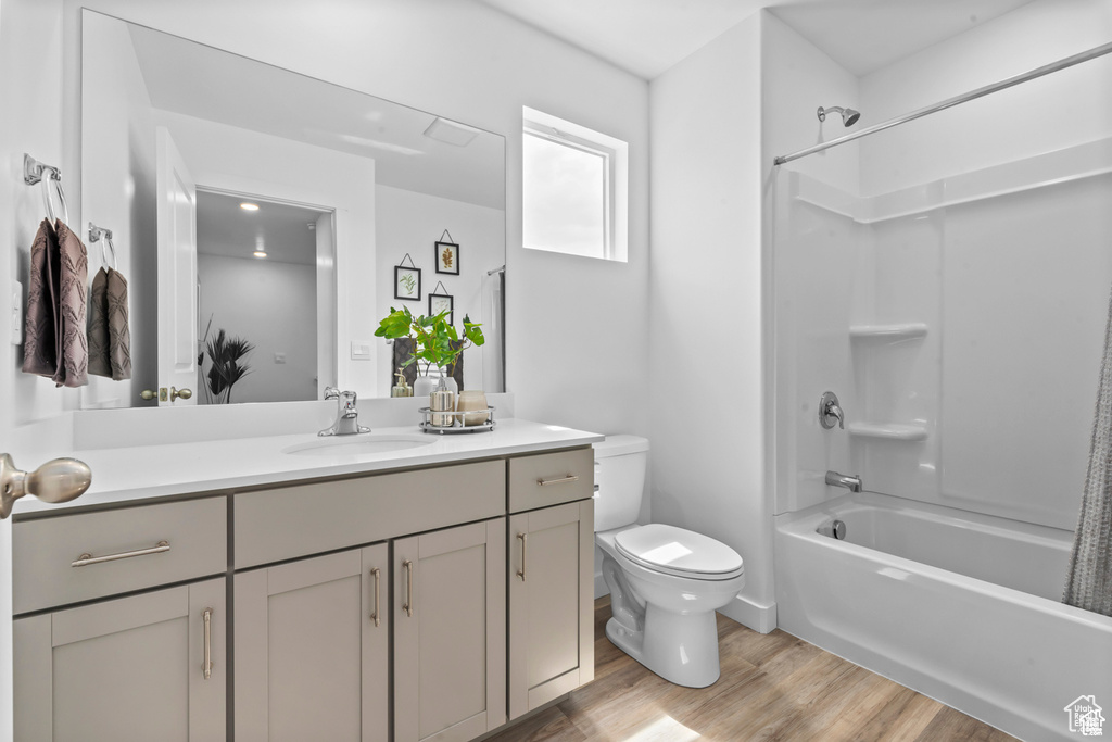 Full bathroom featuring wood-type flooring, vanity, toilet, and shower / tub combo with curtain