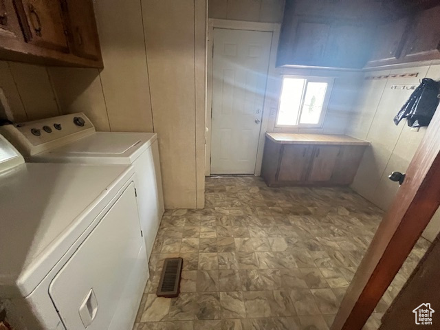 Laundry room featuring separate washer and dryer and cabinets