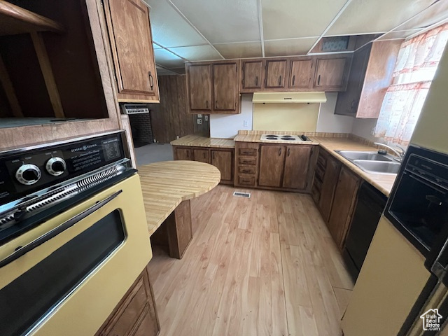 Kitchen featuring a drop ceiling, sink, light hardwood / wood-style floors, white gas stovetop, and stainless steel oven