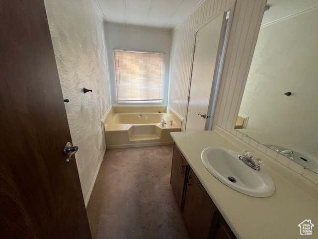 Bathroom with vanity, ornamental molding, and a bath