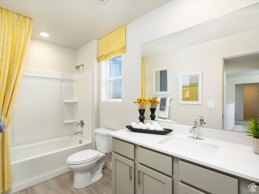 Full bathroom with bathing tub / shower combination, vanity, toilet, and hardwood / wood-style flooring