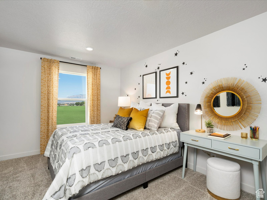 Bedroom with light colored carpet and a textured ceiling