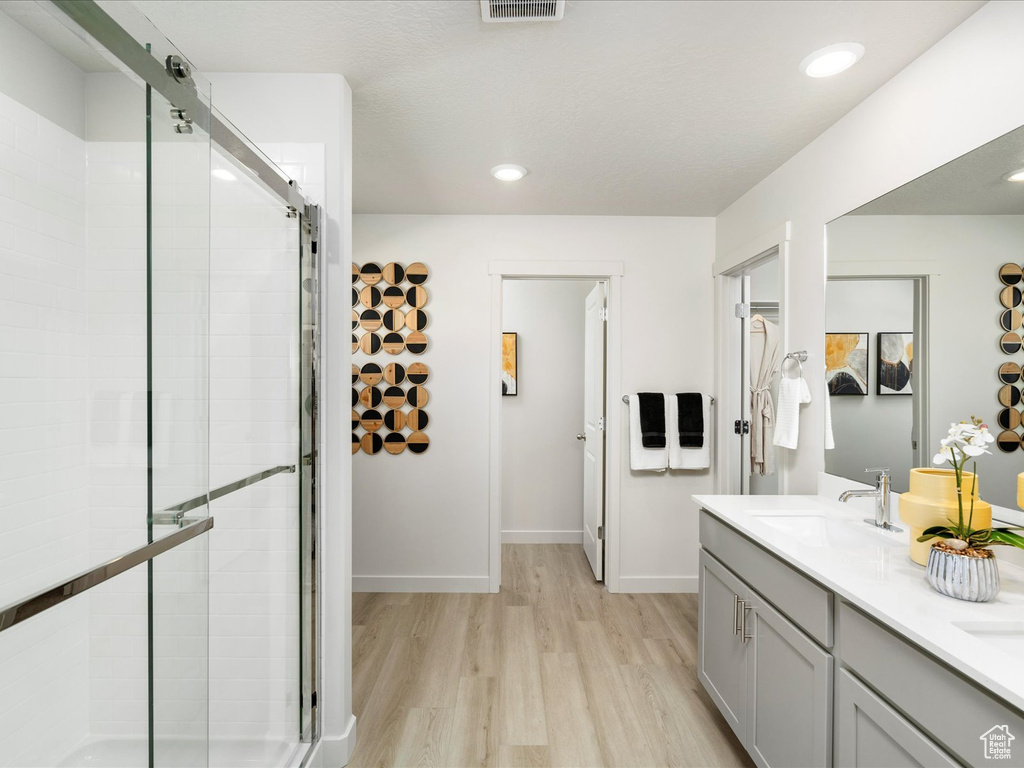 Bathroom with an enclosed shower, vanity, and wood-type flooring