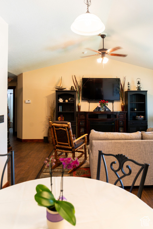 Dining room with ceiling fan, lofted ceiling, and dark wood-type flooring