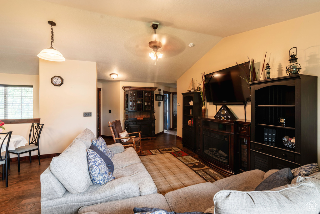 Living room with lofted ceiling, dark hardwood / wood-style floors, and ceiling fan