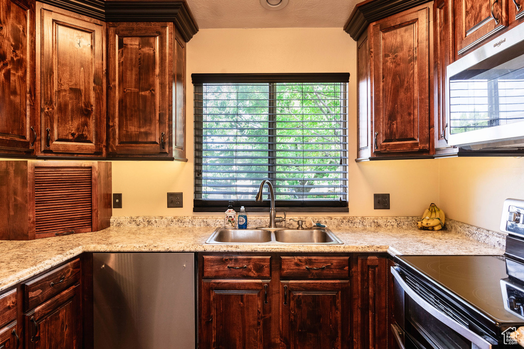 Kitchen with a textured ceiling, stainless steel appliances, sink, and a wealth of natural light