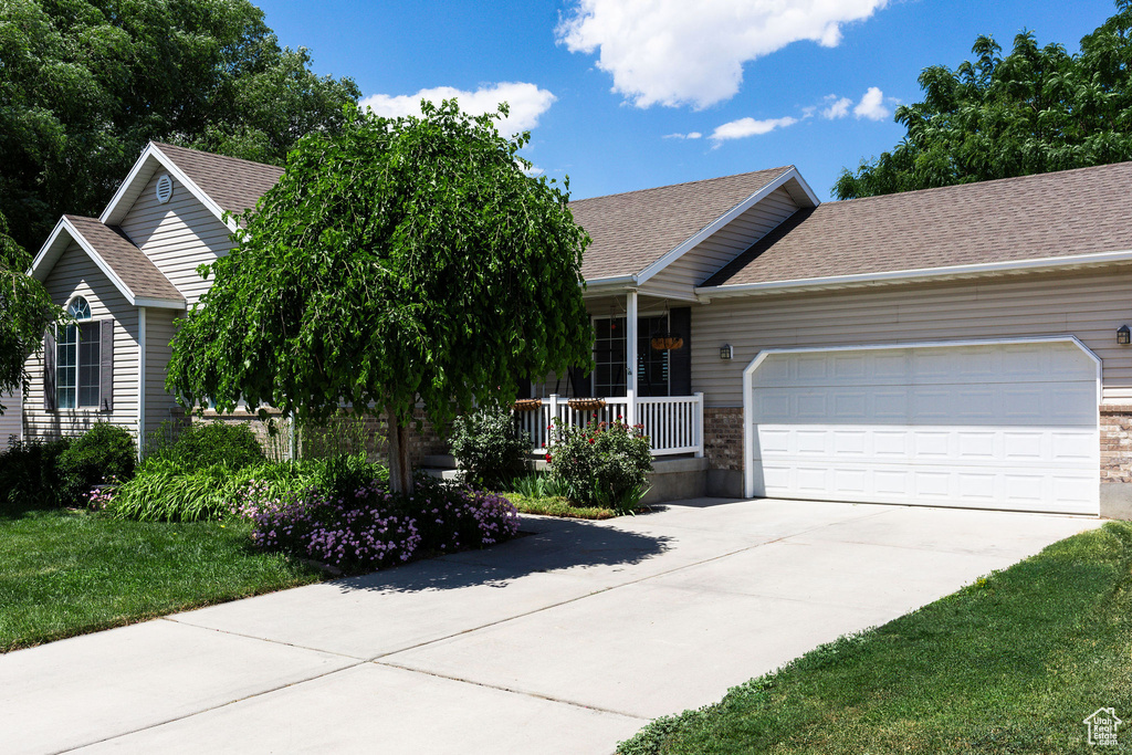 Single story home featuring a garage, a front yard, and covered porch