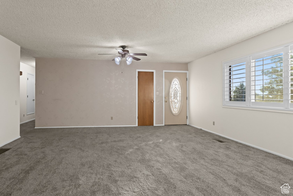 Interior space with dark carpet, a textured ceiling, and ceiling fan