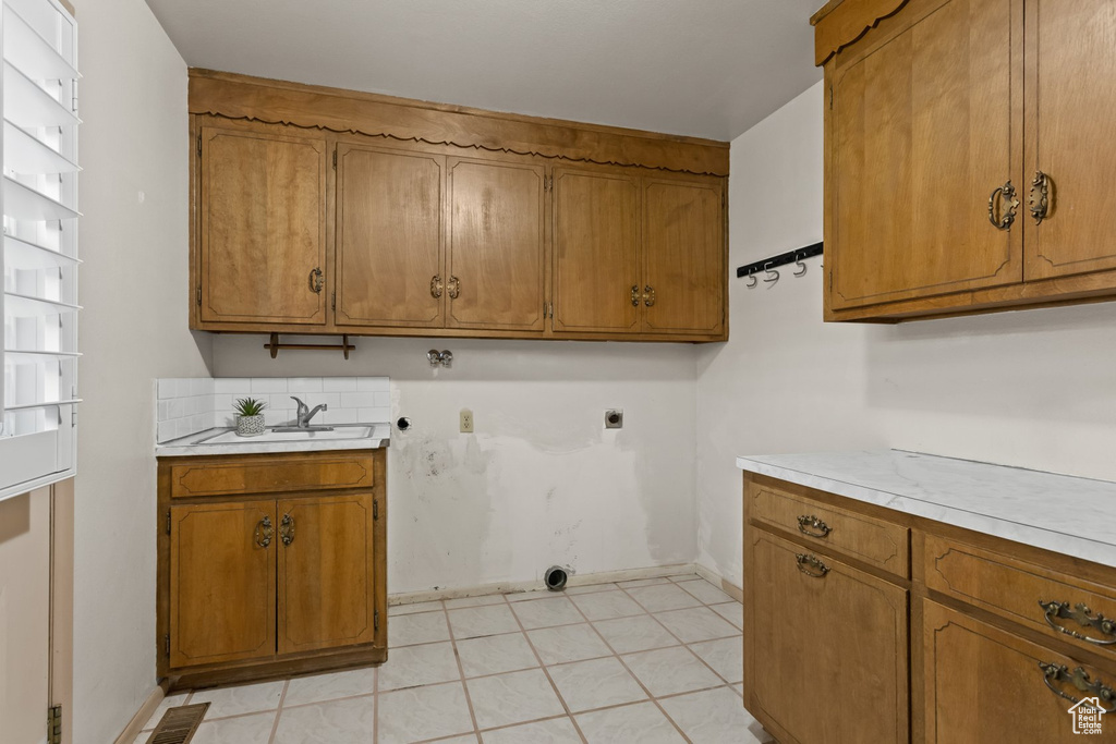 Washroom with sink, cabinets, light tile patterned floors, and electric dryer hookup