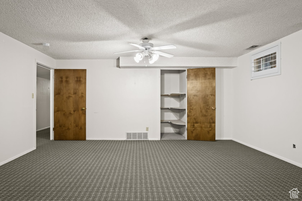 Unfurnished bedroom featuring ceiling fan, a textured ceiling, and dark colored carpet