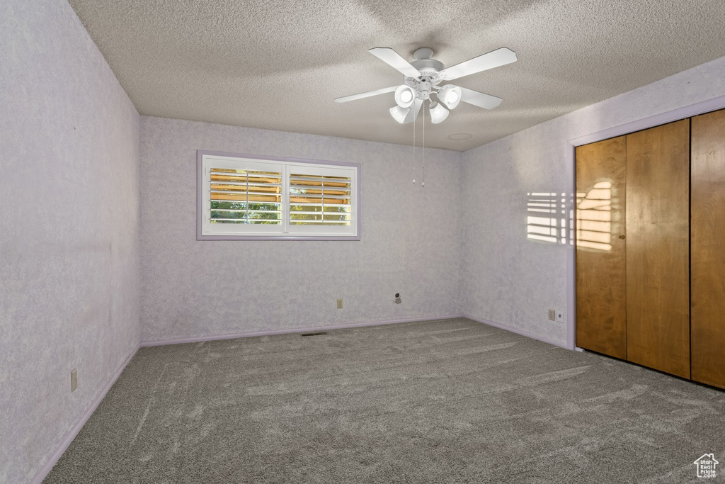 Unfurnished bedroom featuring light carpet, a closet, a textured ceiling, and ceiling fan