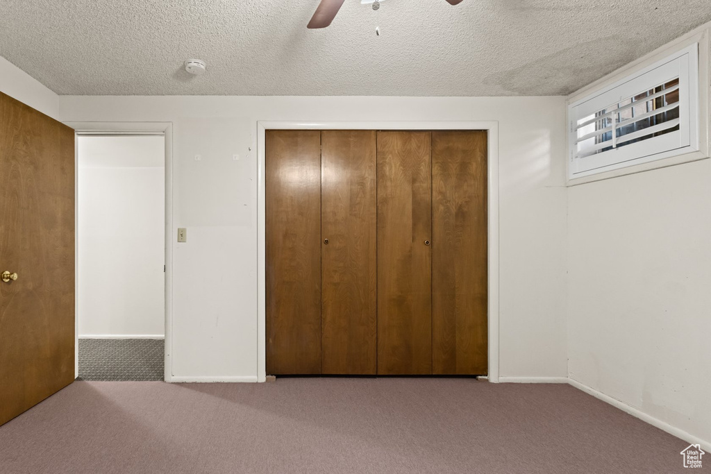 Unfurnished bedroom with a textured ceiling, ceiling fan, a closet, and carpet flooring