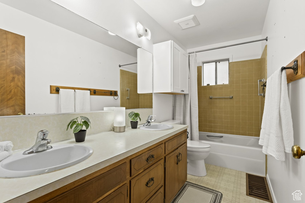 Full bathroom with vanity, shower / tub combo, and toilet