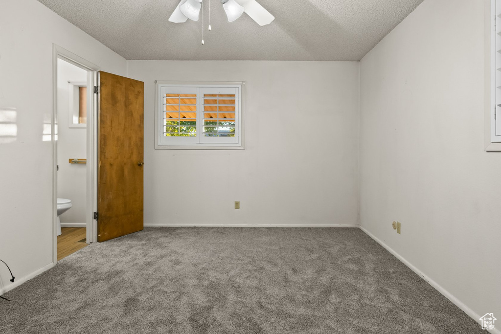 Unfurnished bedroom featuring carpet flooring, ceiling fan, connected bathroom, and a textured ceiling