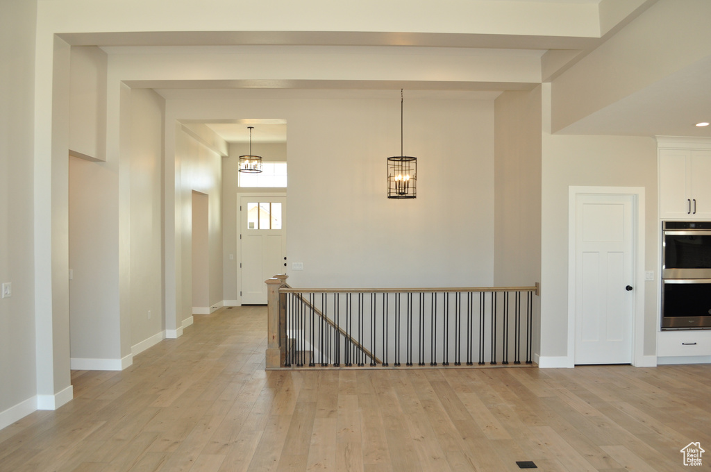 Corridor with a chandelier and light hardwood / wood-style floors