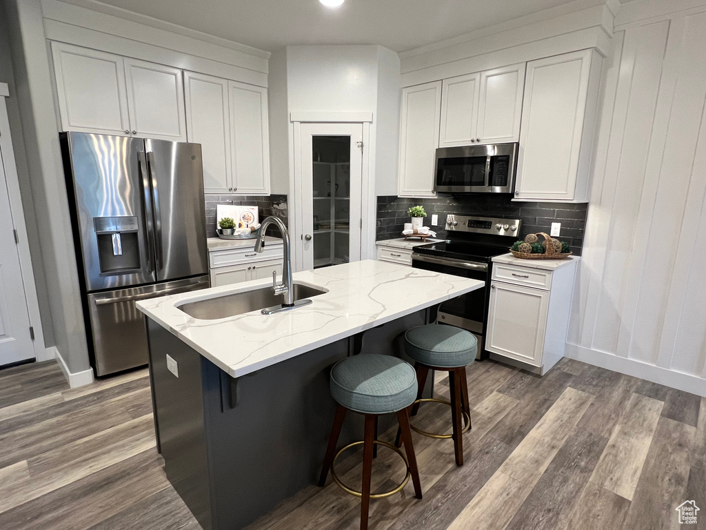 Kitchen featuring a center island with sink, stainless steel appliances, sink, and decorative backsplash