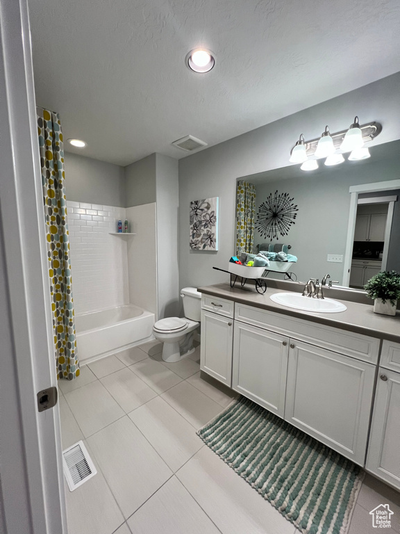 Bathroom with a textured ceiling, tile patterned floors, vanity, and toilet