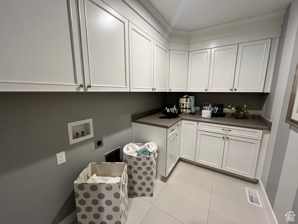 Laundry room featuring washer hookup, hookup for an electric dryer, cabinets, and light tile patterned floors