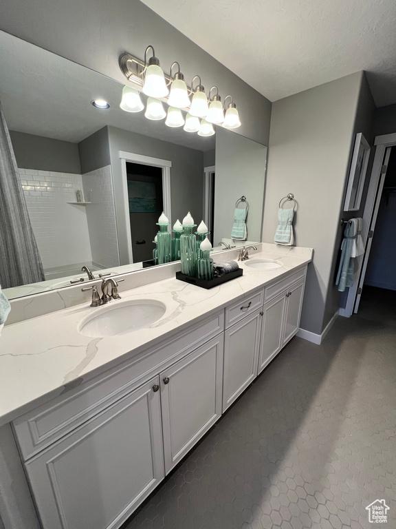 Bathroom featuring a textured ceiling, tile patterned floors, vanity, and tiled shower