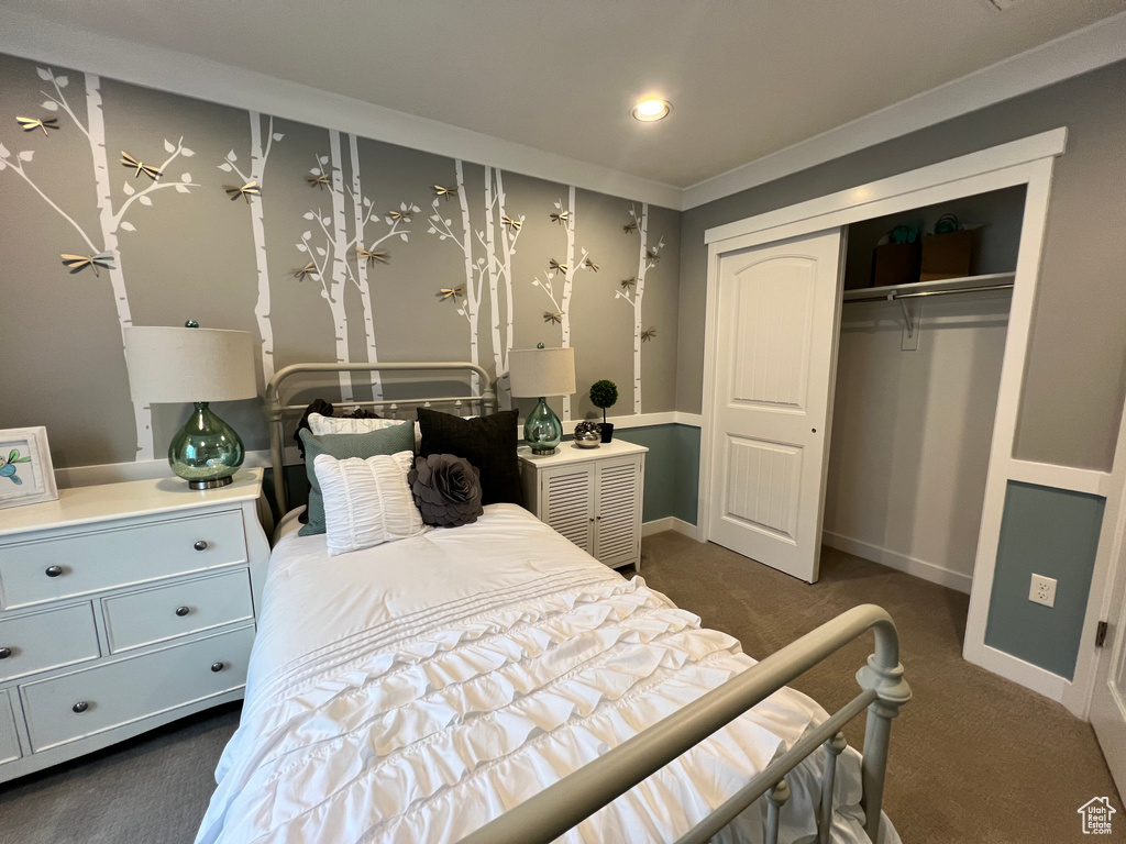 Carpeted bedroom with a closet and crown molding