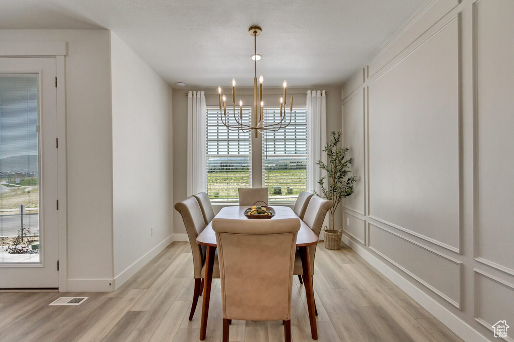 Dining space with an inviting chandelier, light hardwood / wood-style flooring, and a healthy amount of sunlight